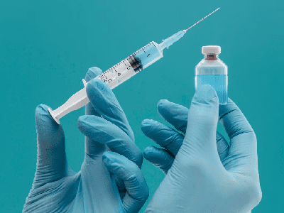 Vaccine bottle and syringe held by doctor with gloves<br />
